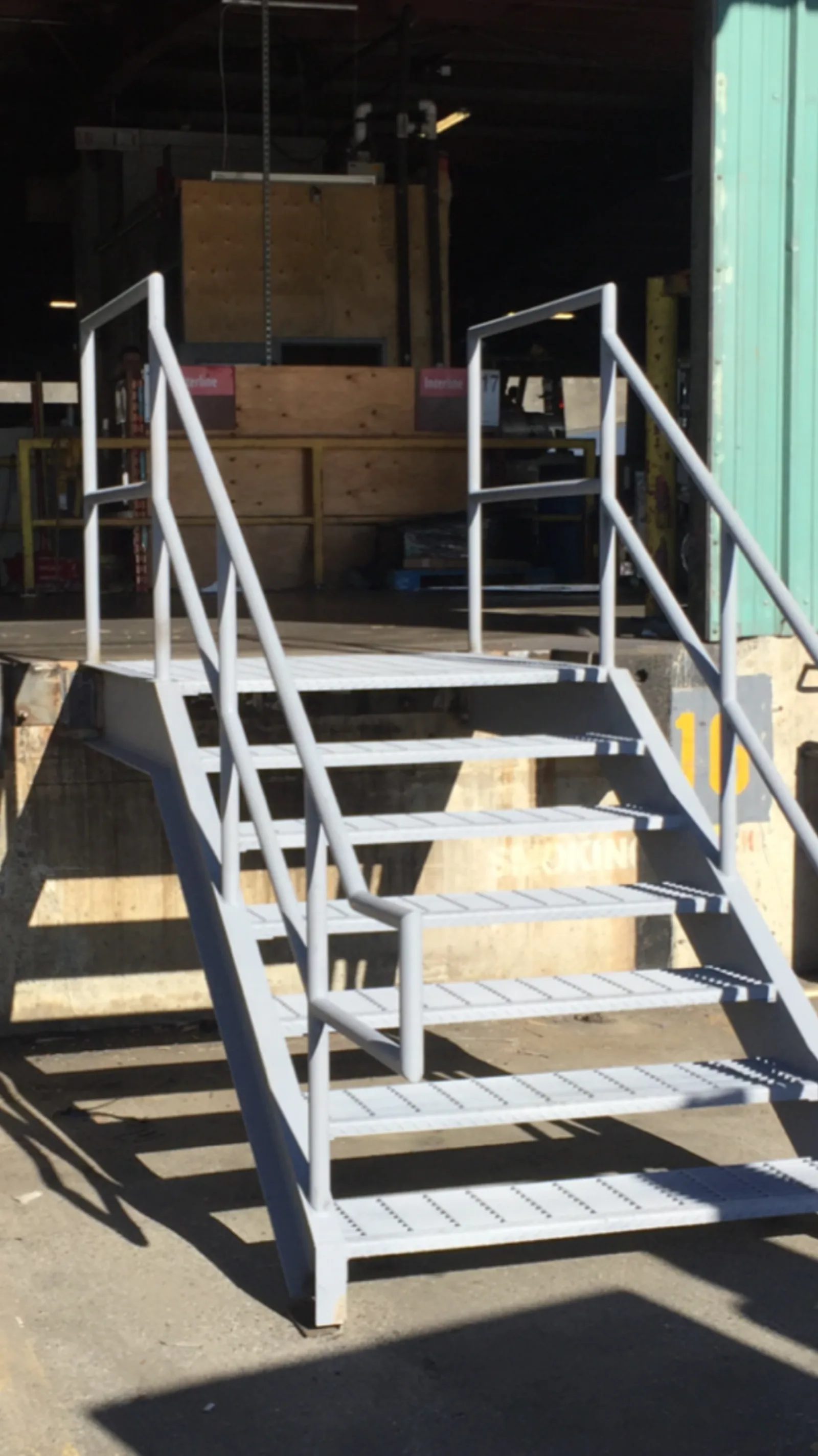 New warehouse access stair in our shop with double stringers, bar grating treads, and tubular pipe-rail guards before paint — the standard detail we ship for exterior commercial use